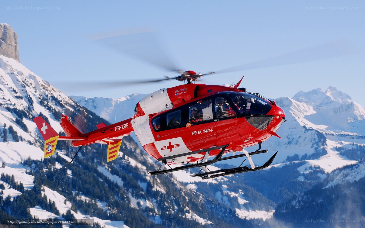 Red rescue helicopter over snowy mountains