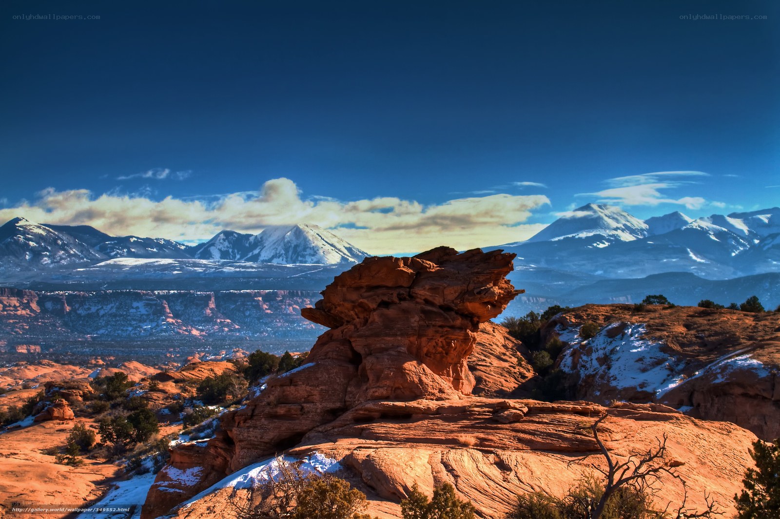 Red rock formation with snow-capped mountains