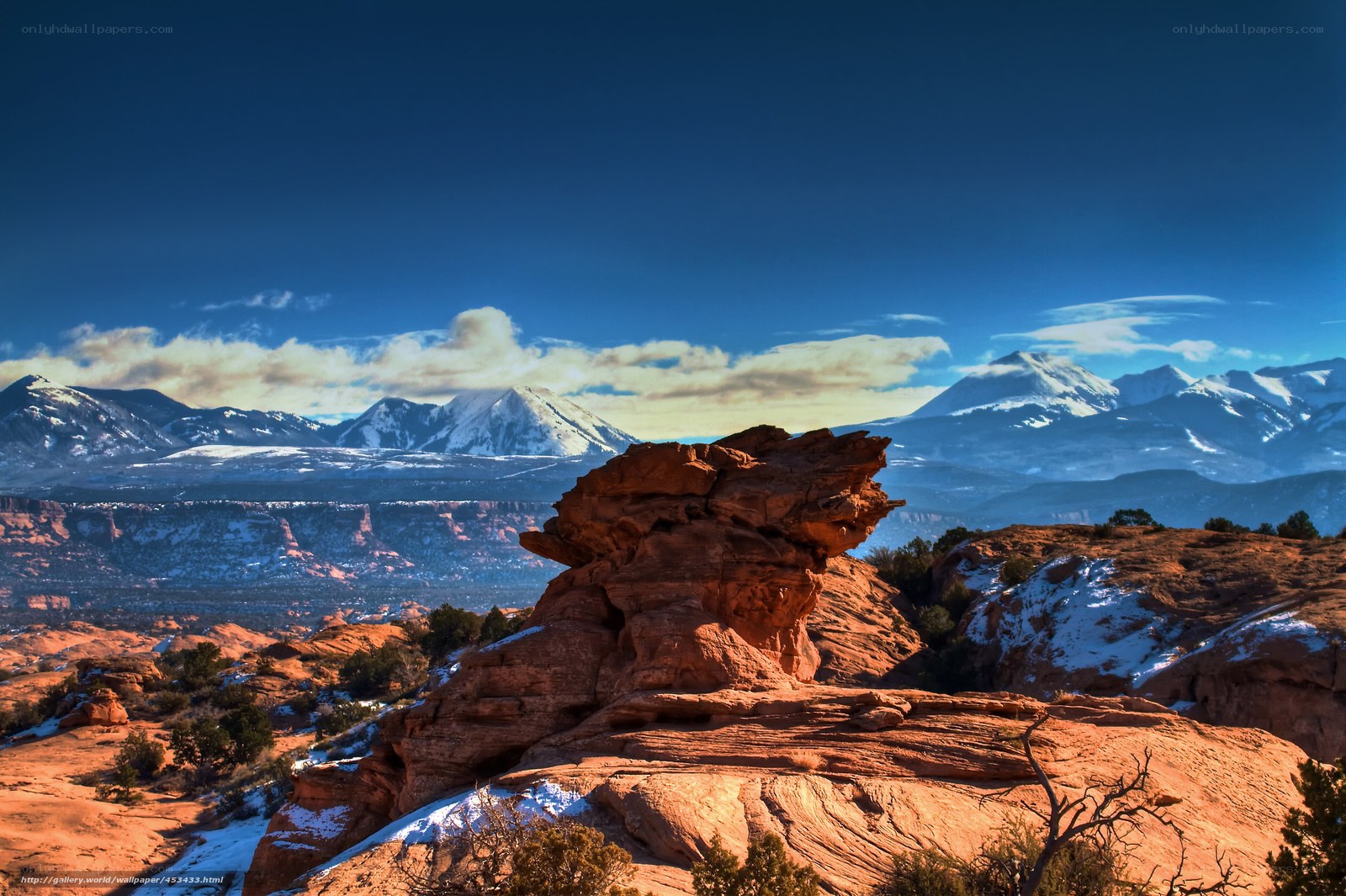 Red rock formation with snow-capped mountains