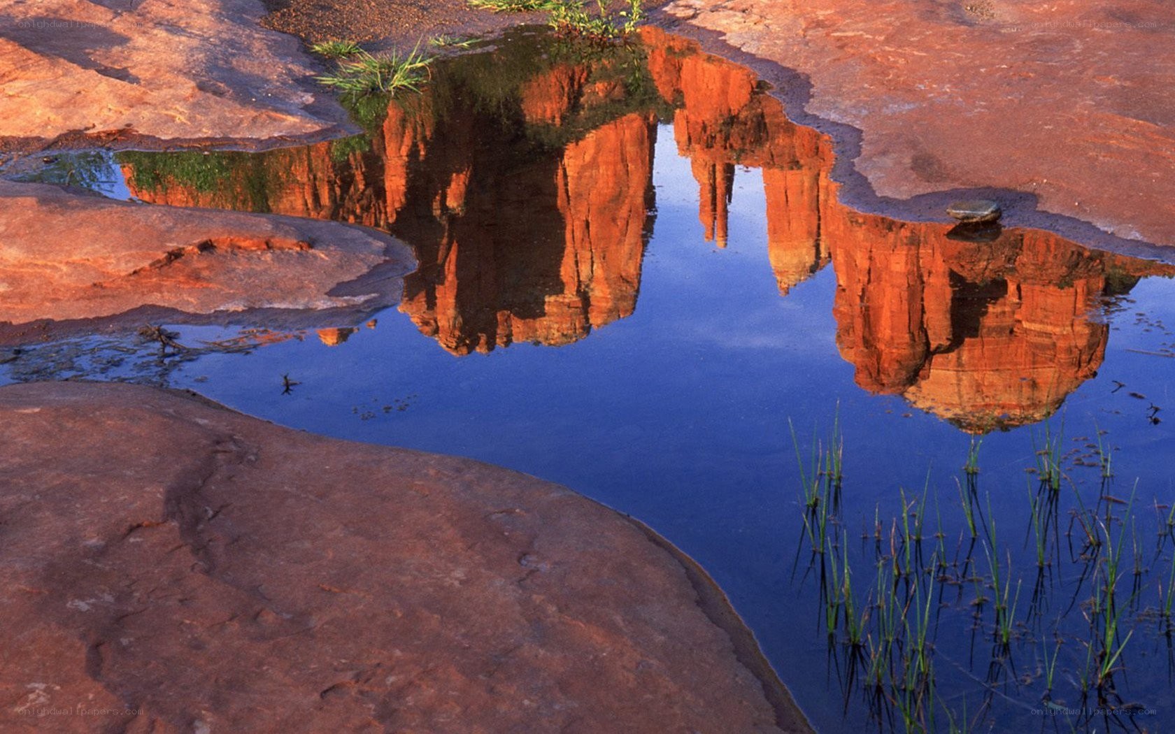 Red rock formations reflected in water