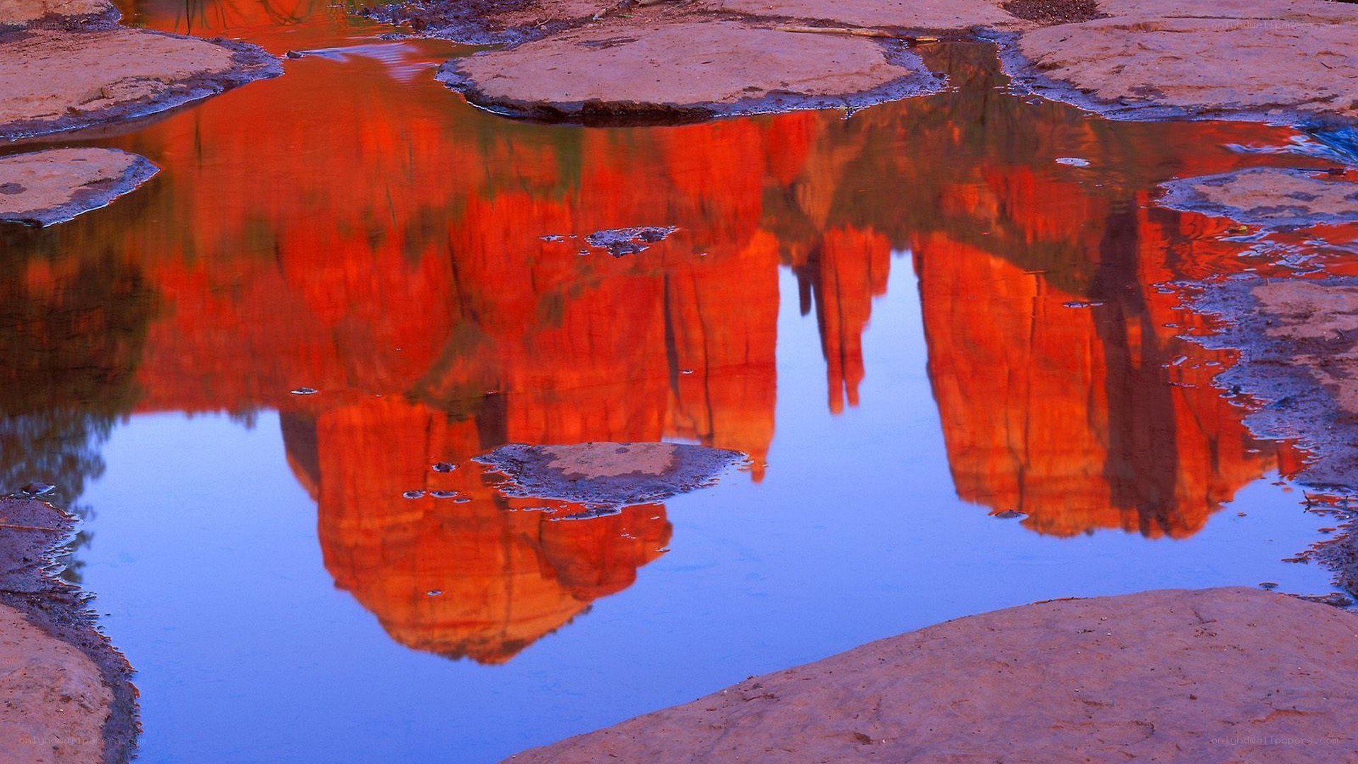 Red rock formations reflected in water