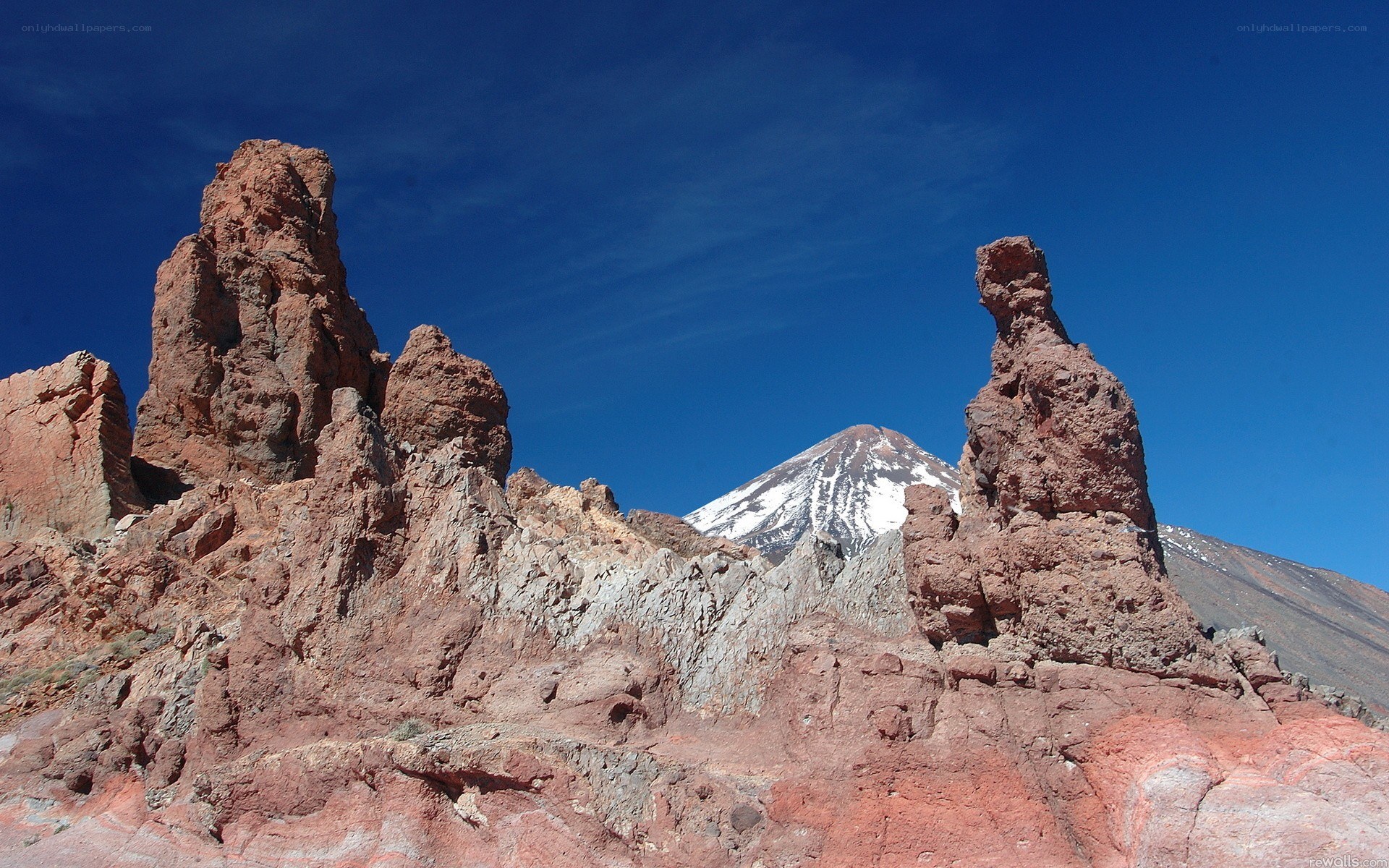 Red rock formations with snow-capped mountain