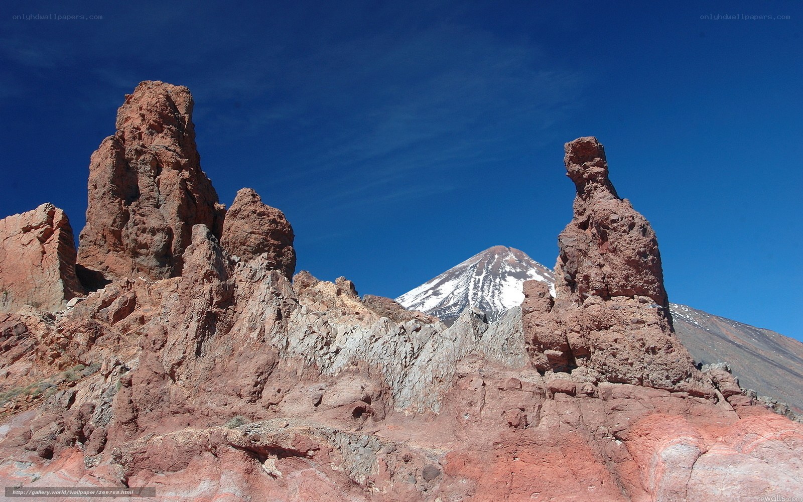 Red rock formations with snow-capped mountain