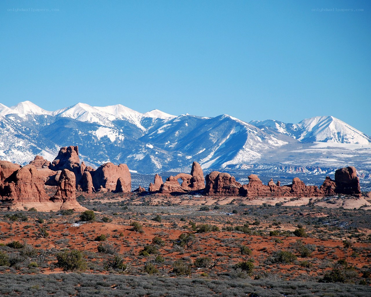 Red rock formations with snow-capped mountains