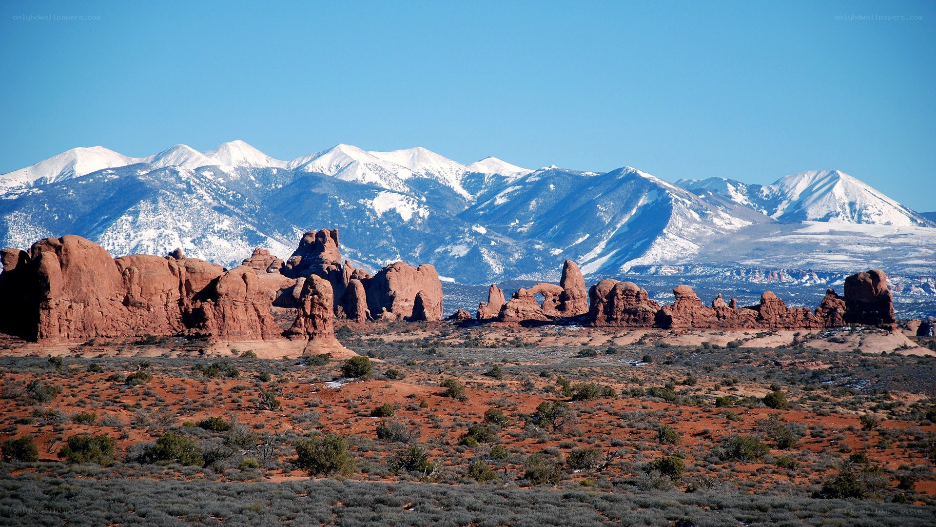 red rock formations with snow-capped mountains