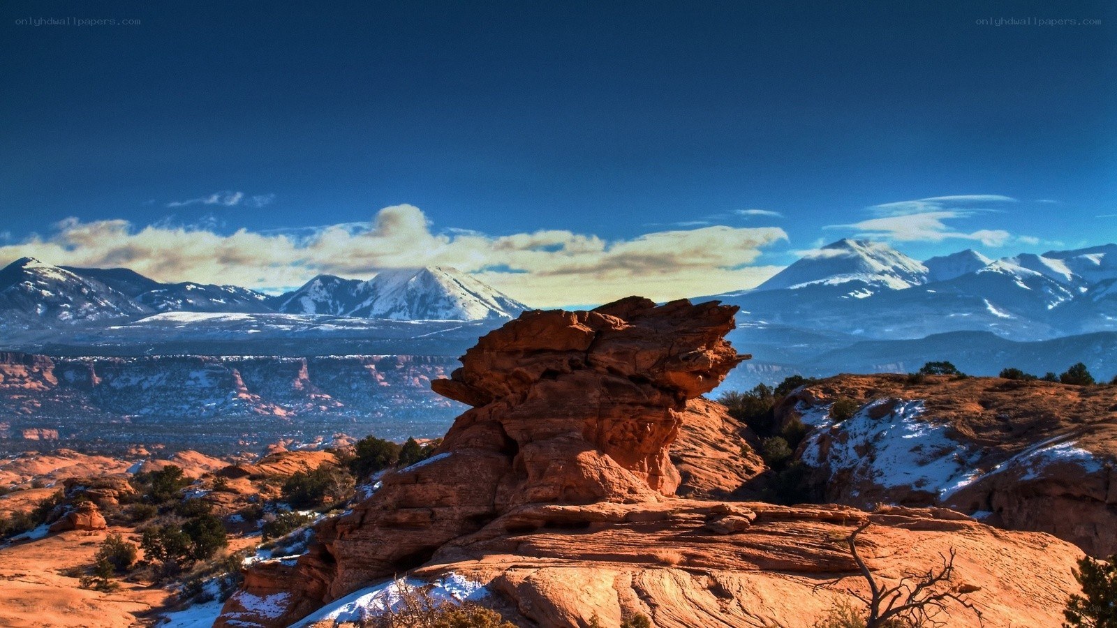 Red rock formations with snow-capped mountains