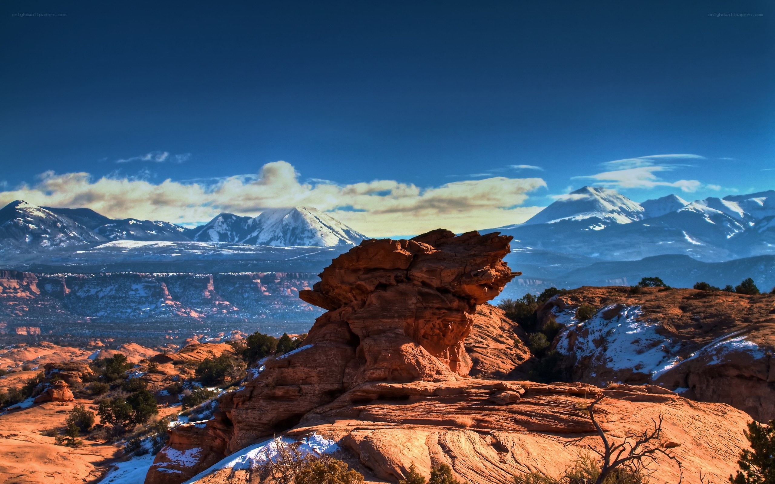 Red rock formations with snow-capped mountains