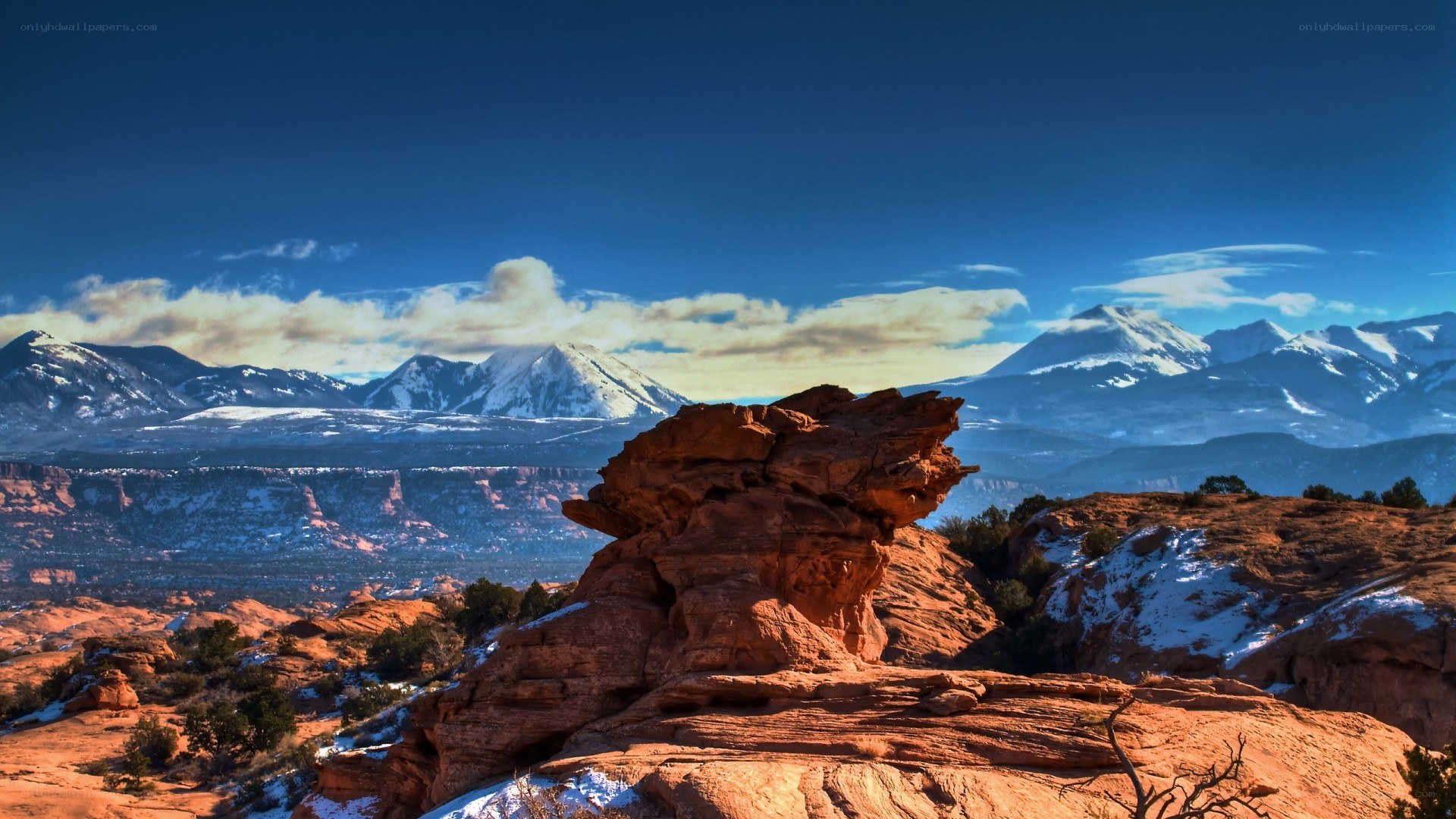 Red rock formations with snow-capped mountains