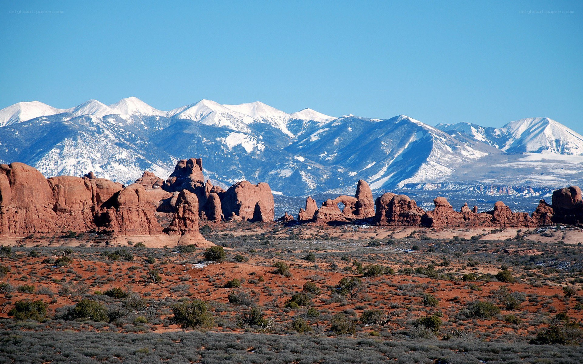 Red rock formations with snow-capped mountains