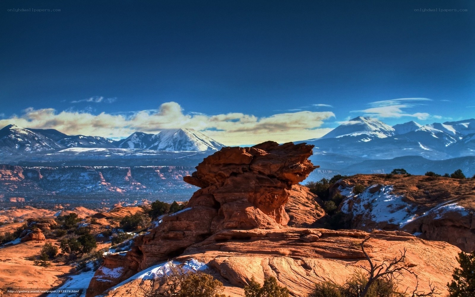 Red rock formations with snow-capped mountains