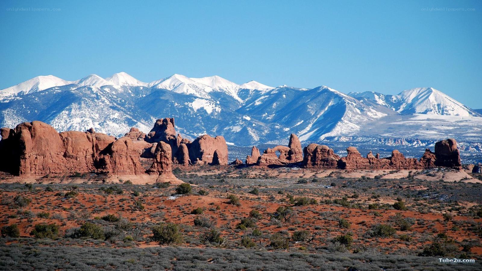 red rock formations with snow-capped mountains
