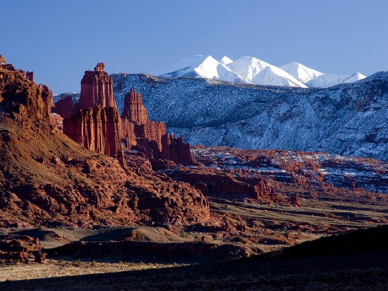 Red rock formations with snow-capped mountains