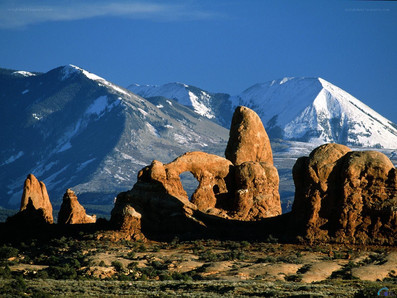 Red rock formations with snow-capped mountains