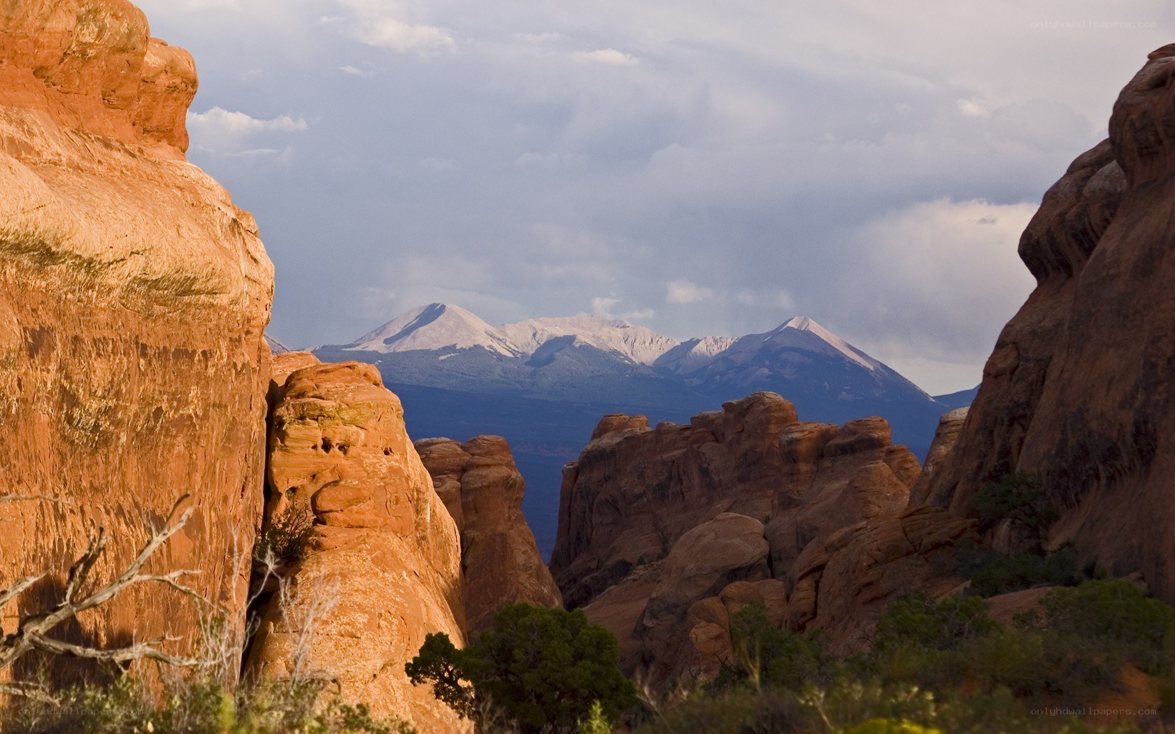 Red rock formations with snow-capped mountains