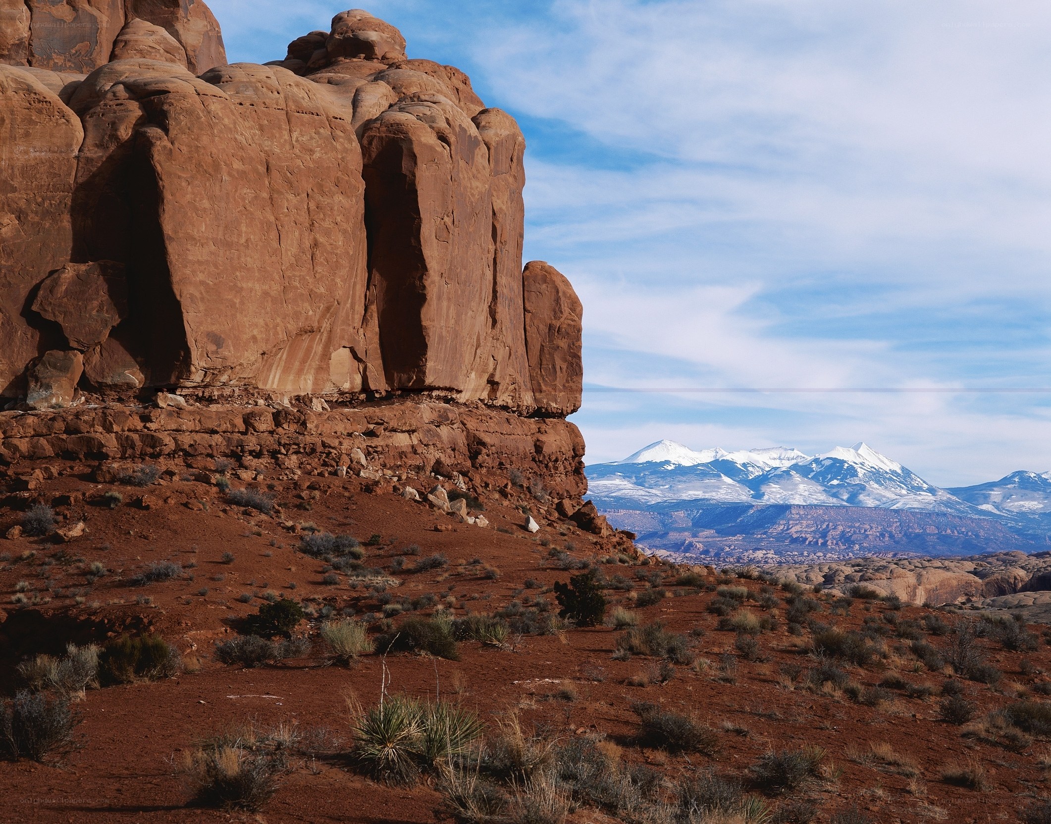 Red rock formations with snow-capped mountains