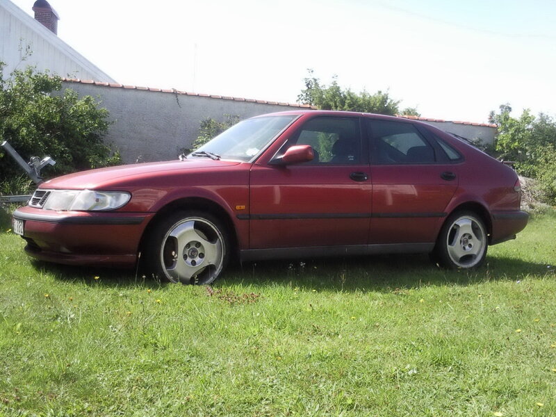 red saab sedan on grass