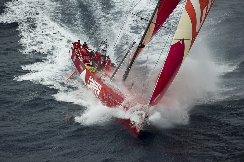 Red sailboat racing in rough seas