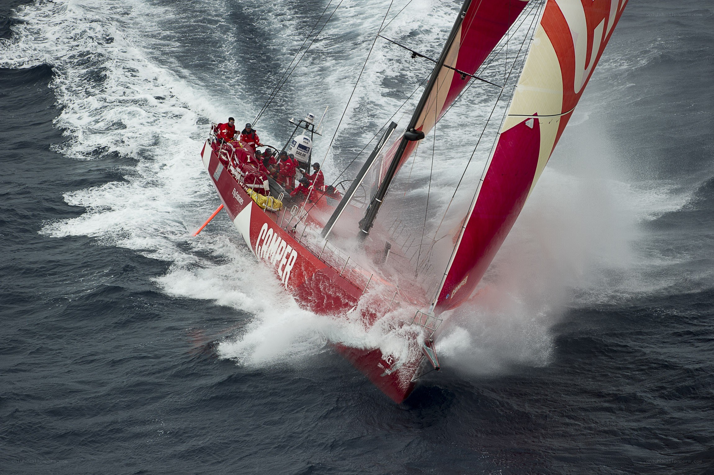 Red sailboat racing in rough seas