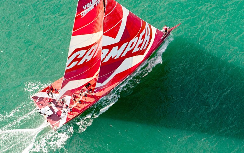 Red sailboat racing on green water
