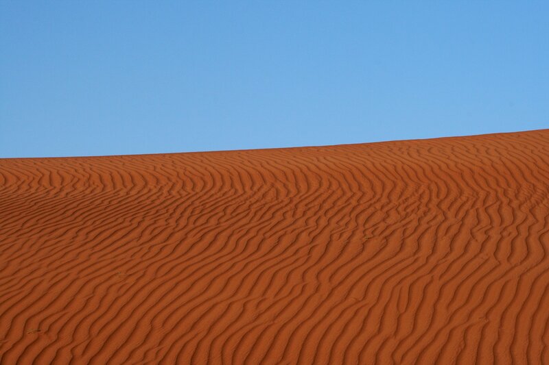 Red sand dunes under blue sky