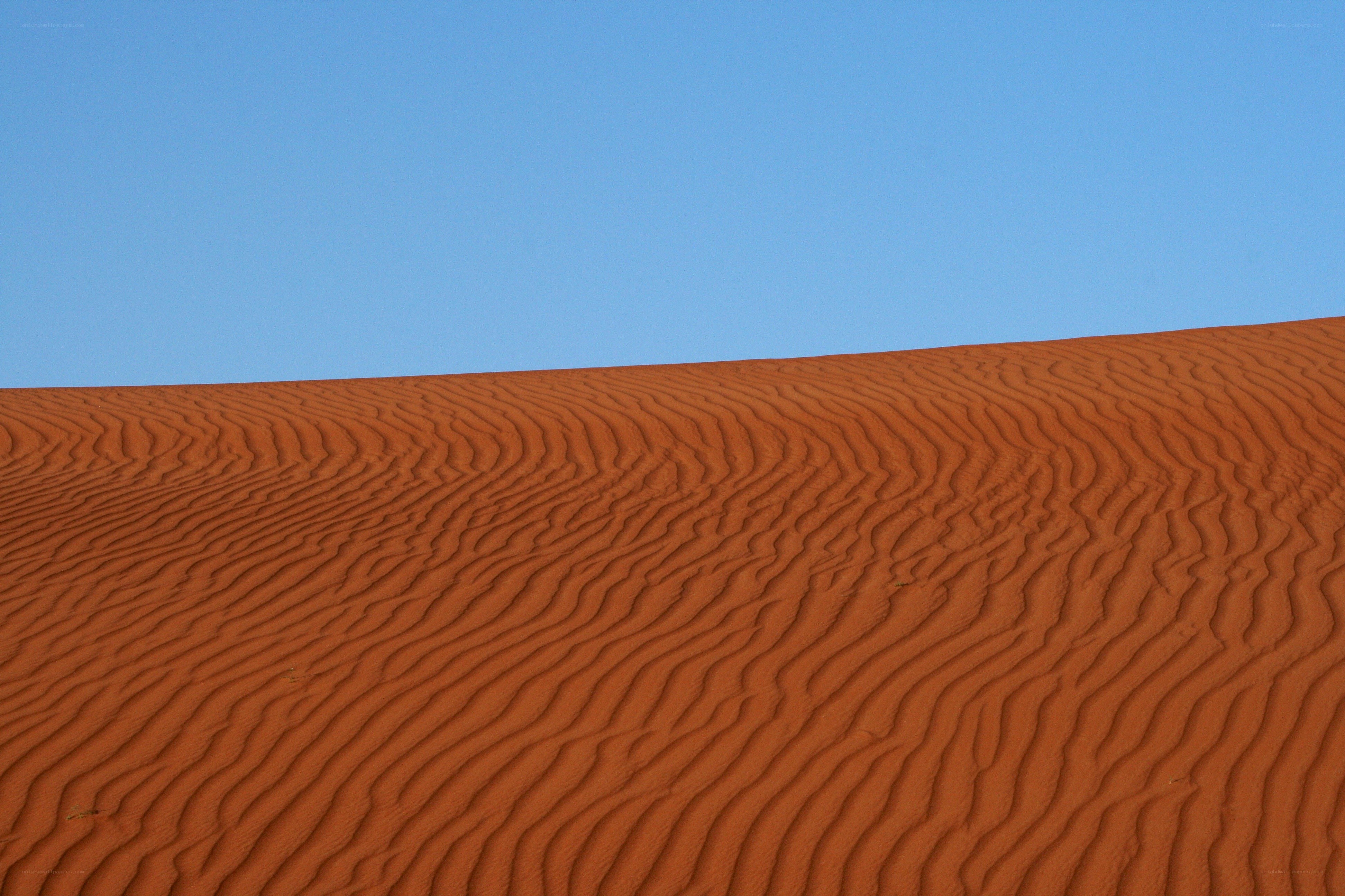 Red sand dunes under blue sky