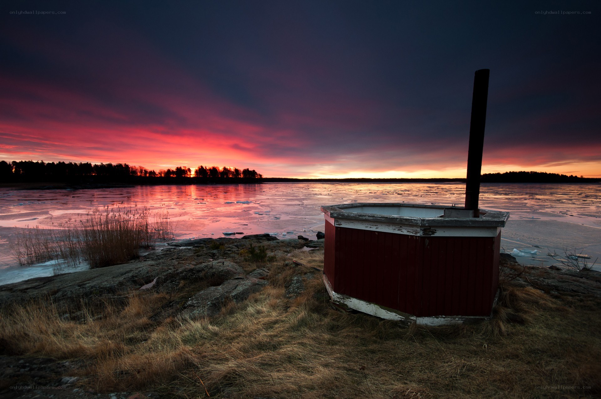 Red sauna by a frozen lake