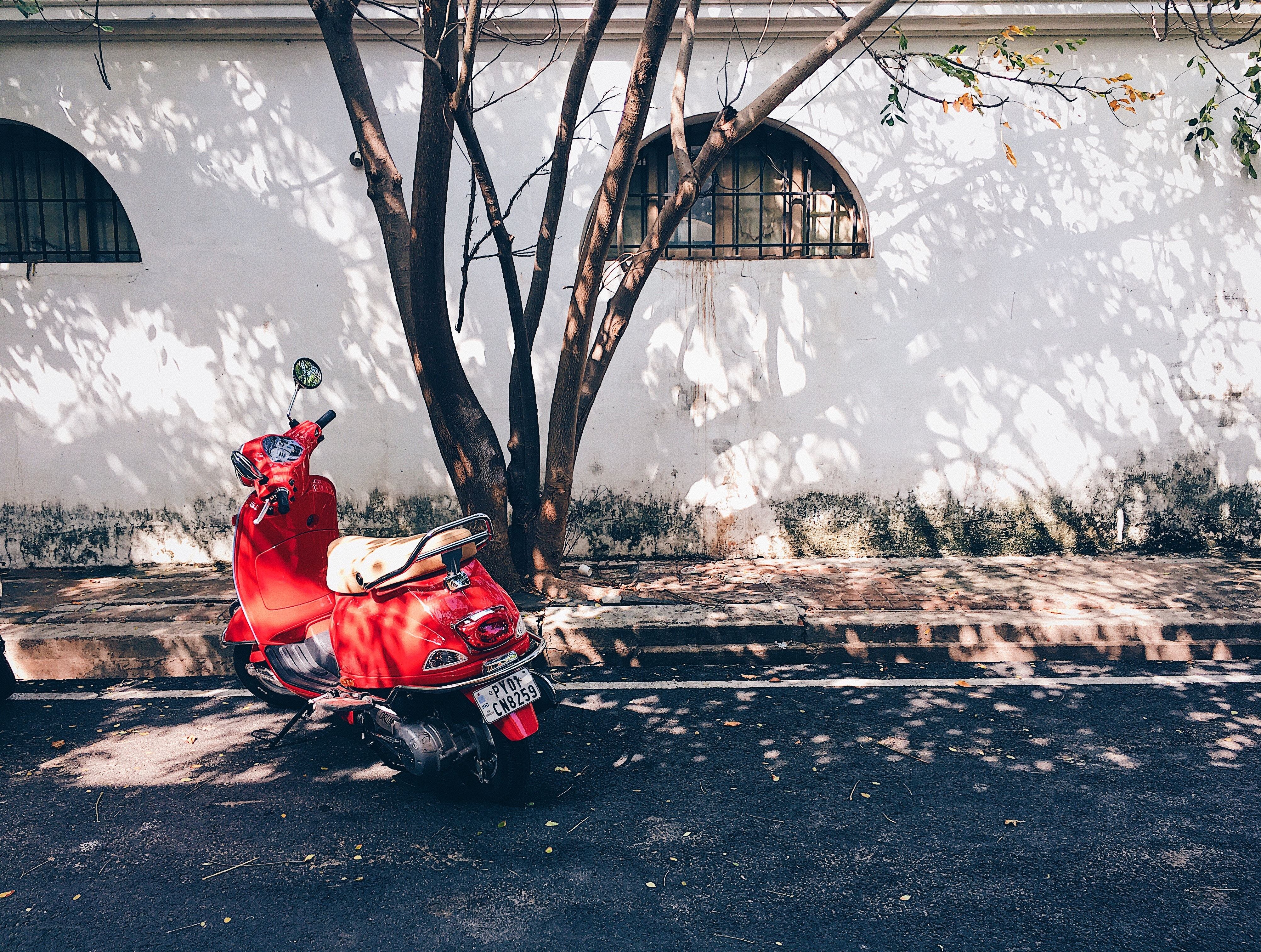 Red scooter parked by a wall