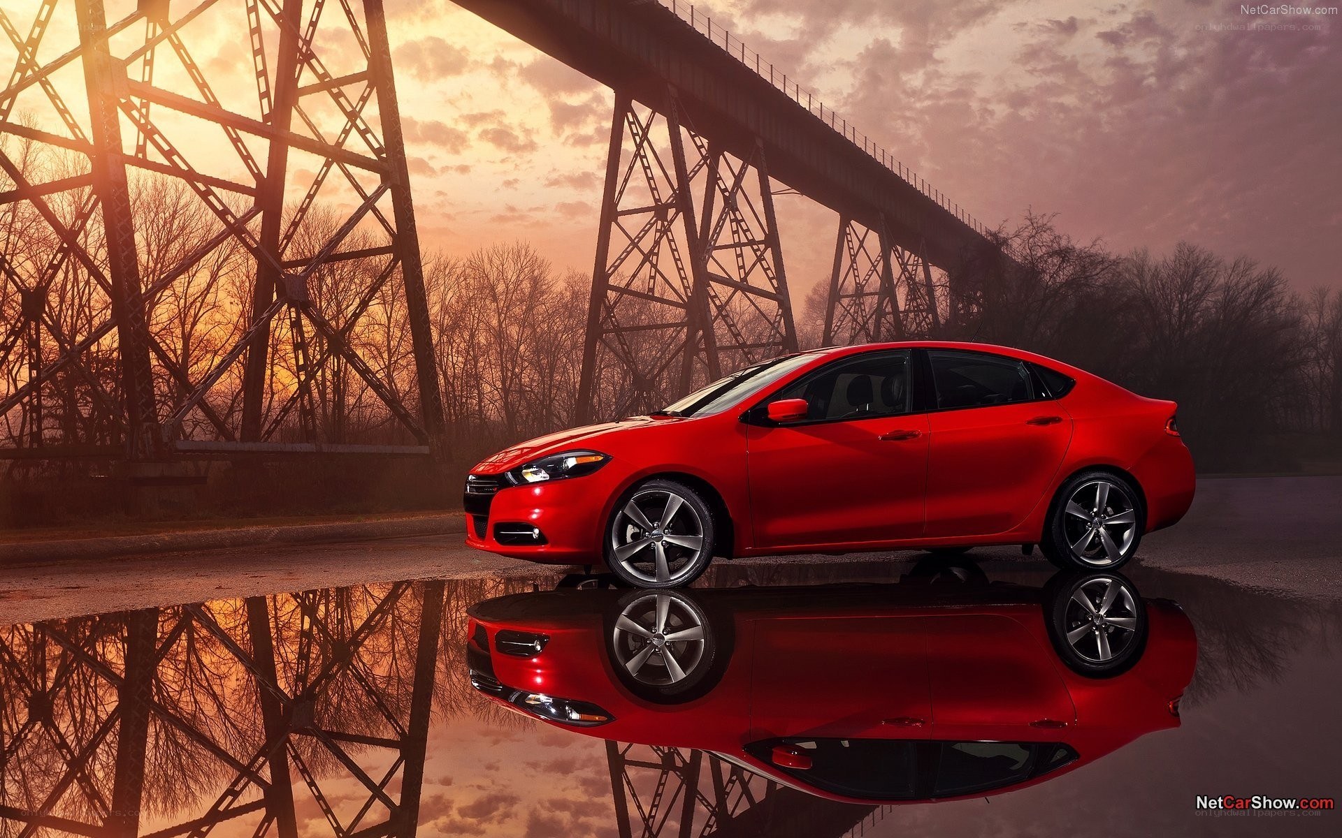 Red sedan by a bridge at sunset