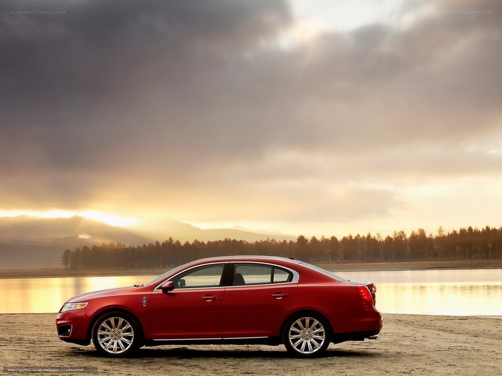 Red sedan by a lake at sunset