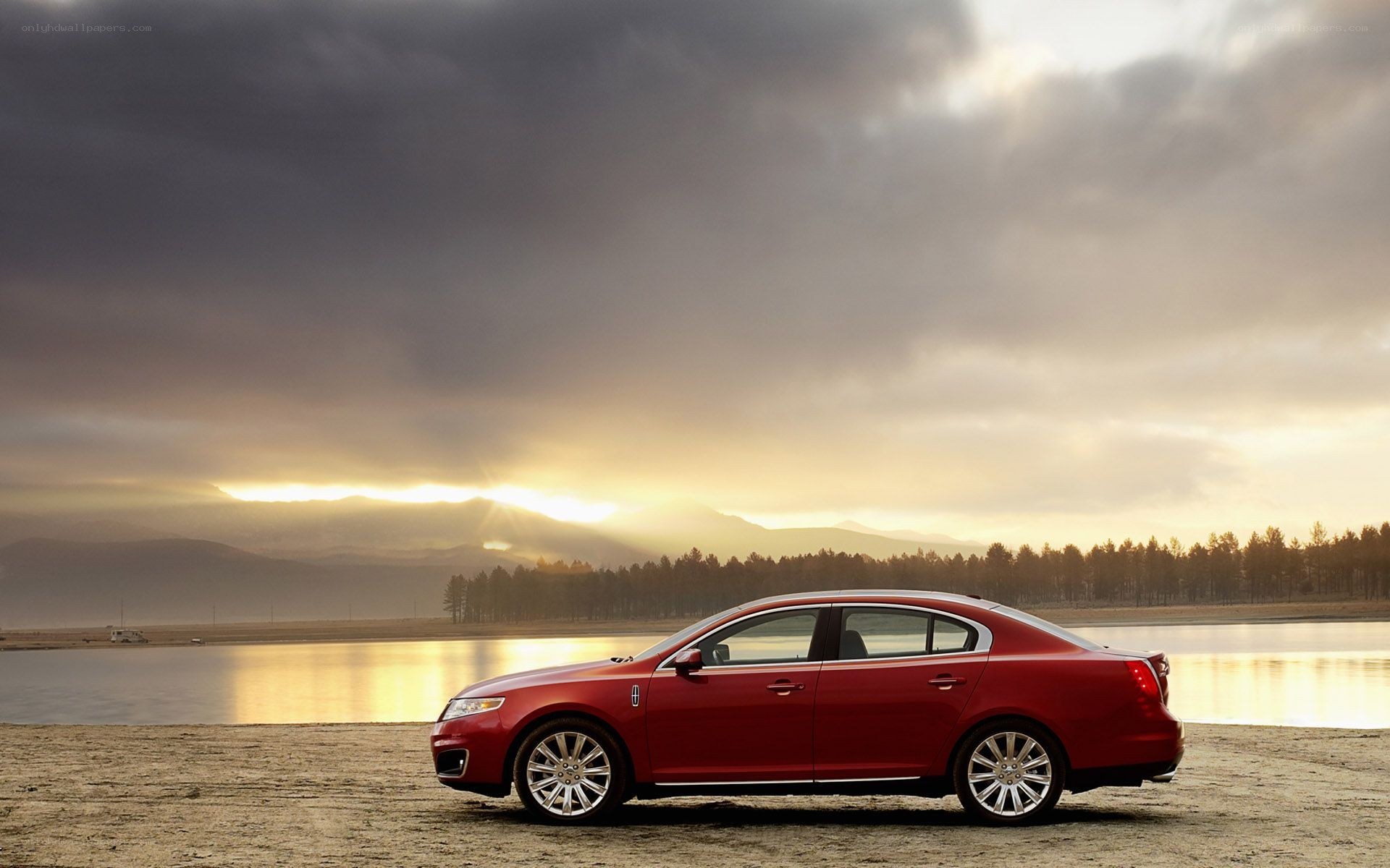 Red sedan by lake at sunset