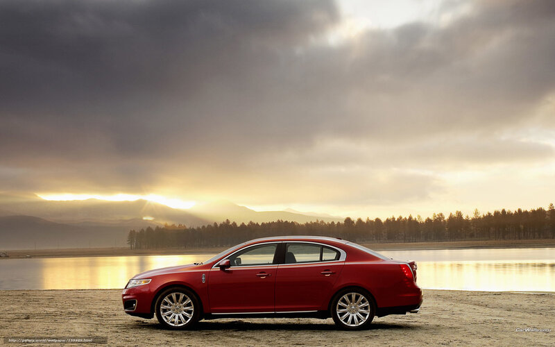 Red sedan by lake at sunset