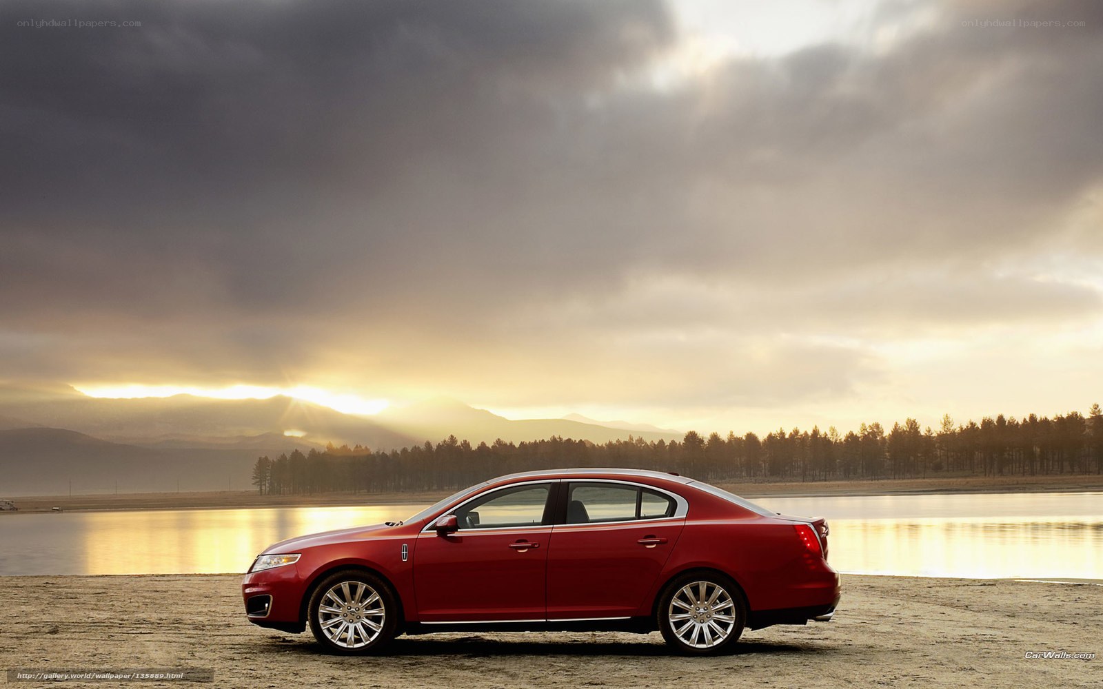 Red sedan by lake at sunset