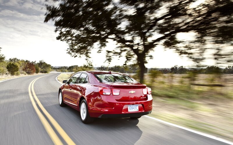Red sedan driving on country road