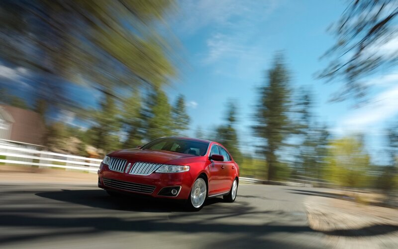 Red sedan driving on country road