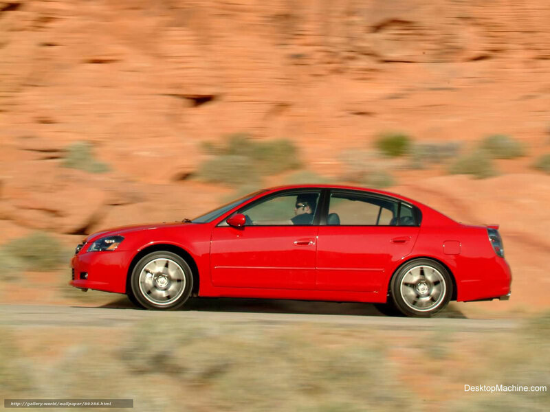 Red sedan driving on desert road