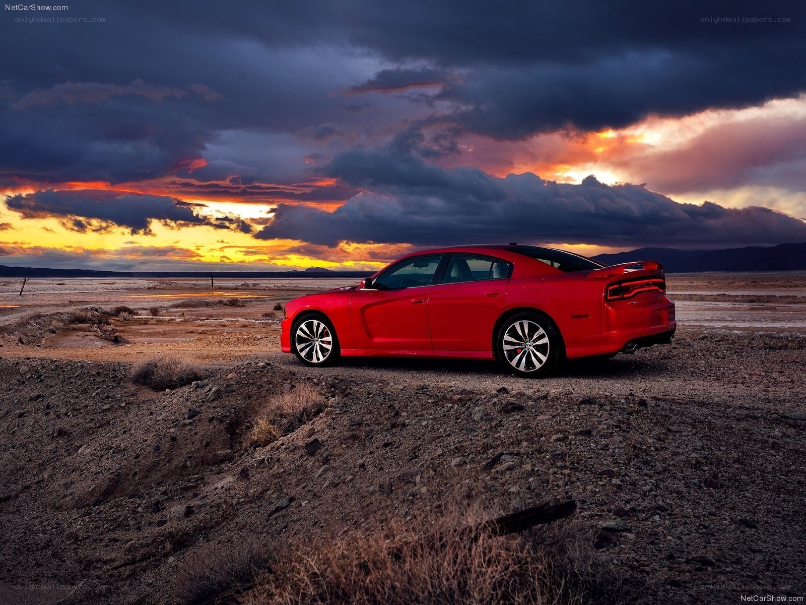 Red sedan in desert at sunset