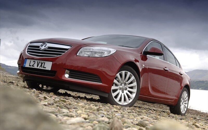 Red sedan on a pebble beach