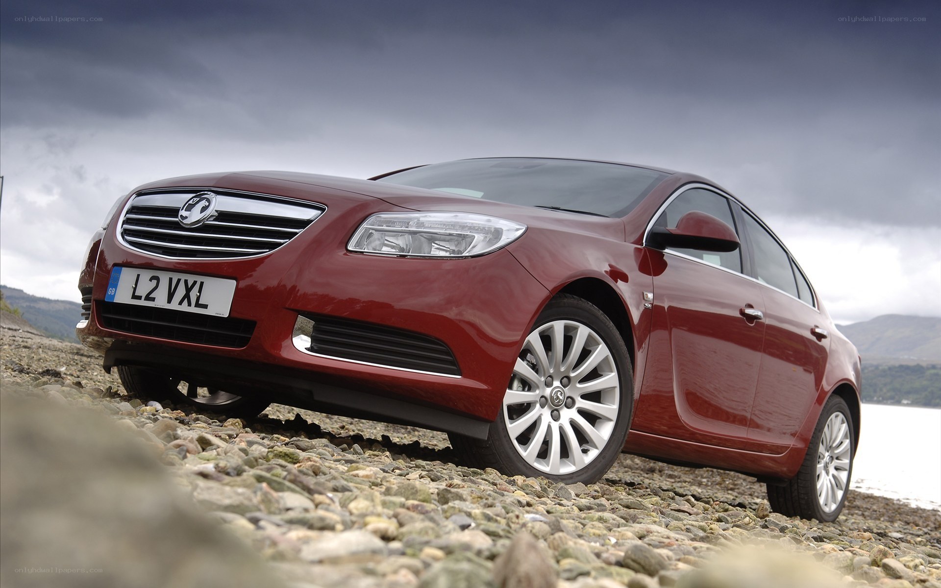 Red sedan on a pebble beach