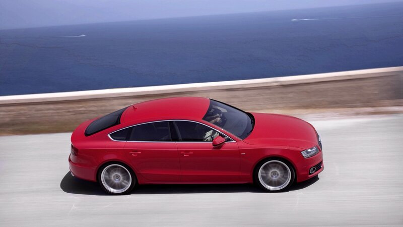 Red sedan on coastal road