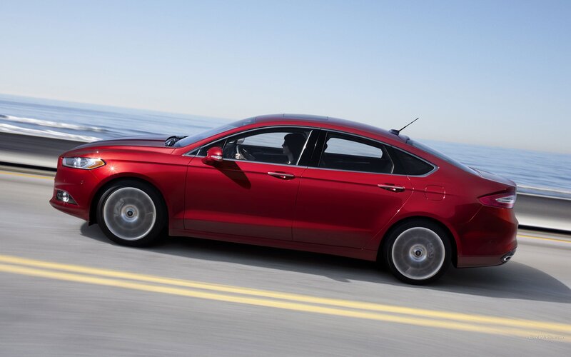 Red sedan on coastal road