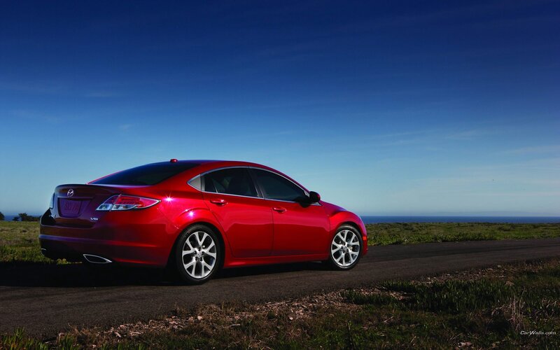 Red sedan on coastal road