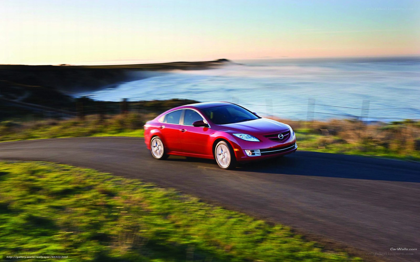 Red sedan on coastal road