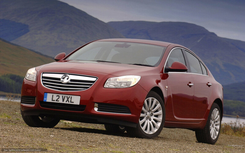 Red sedan on gravel with mountains