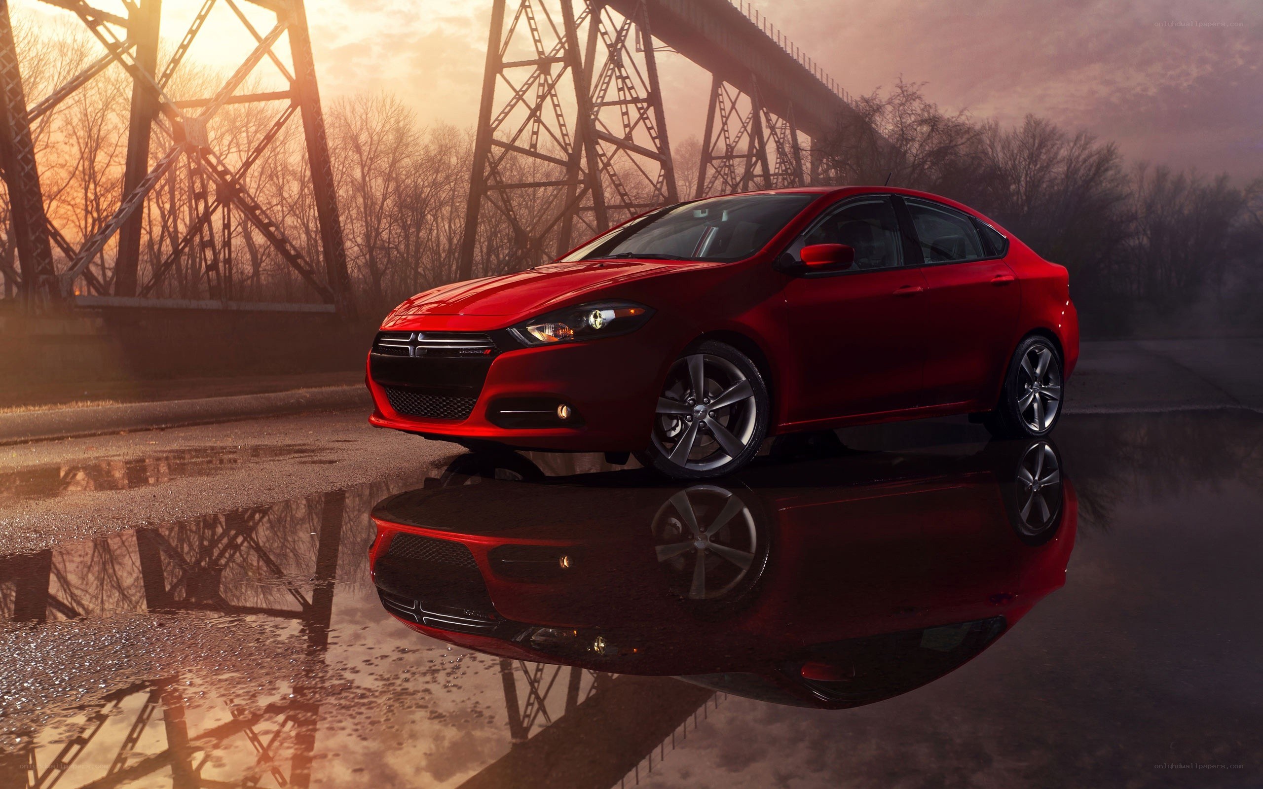 Red sedan on wet road at sunset
