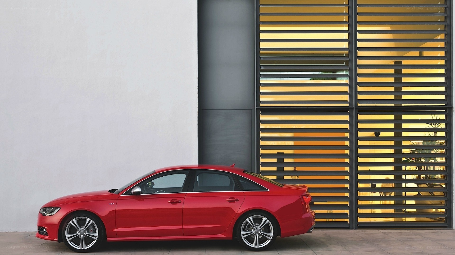 Red sedan parked by modern building