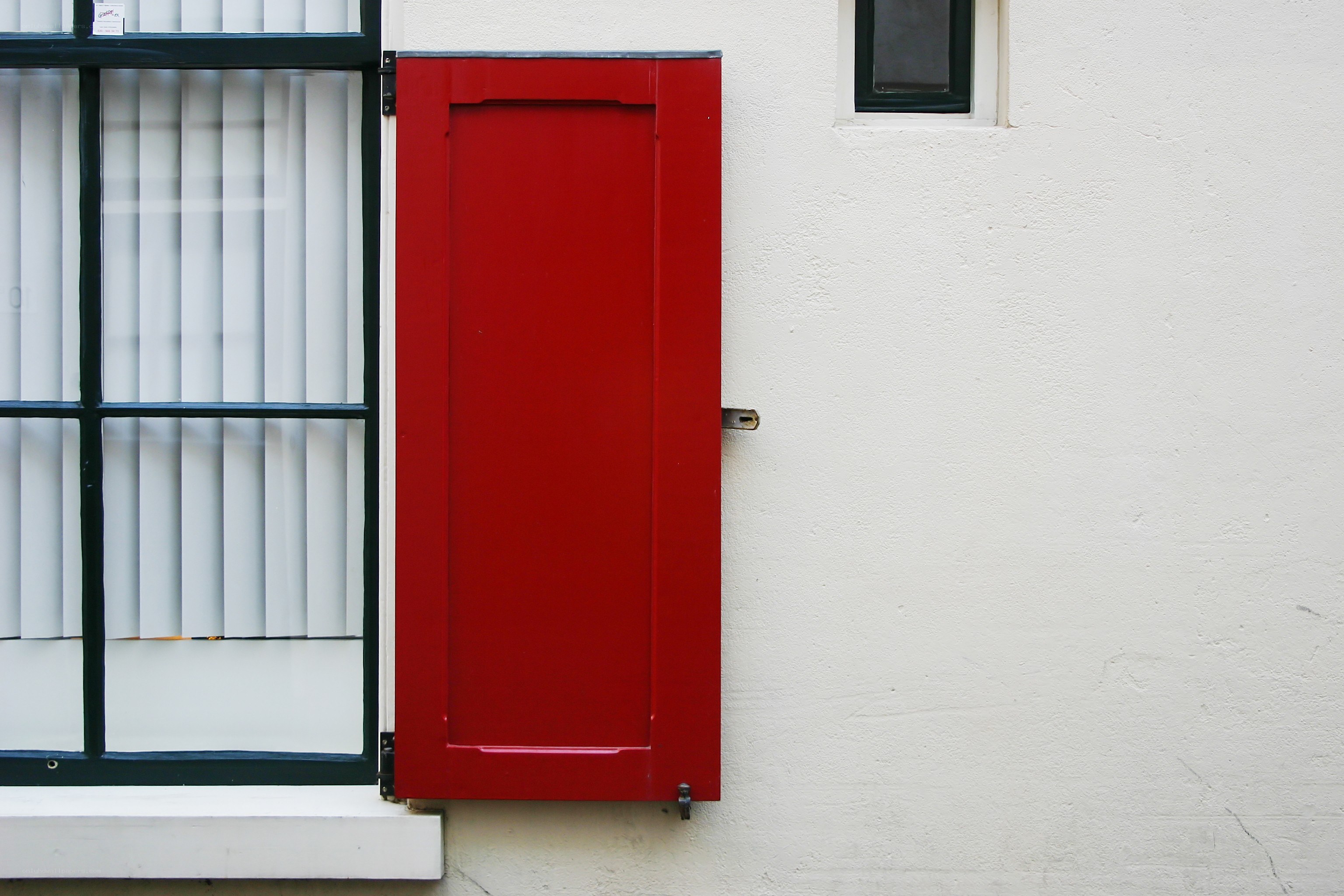 Red shutter on white wall