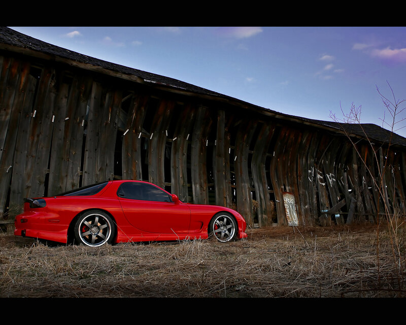 Red sports car by old barn