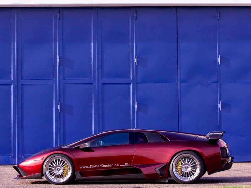 Red sports car in front of blue garage
