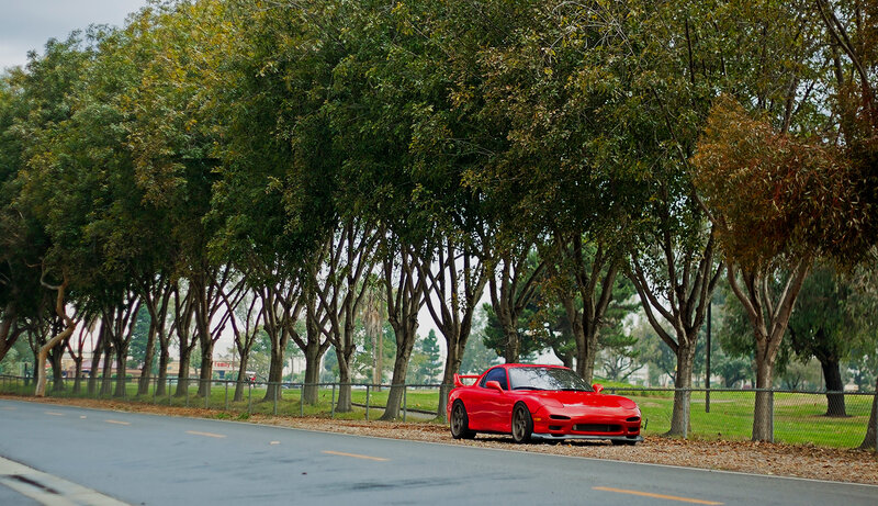 Red sports car on a tree-lined road