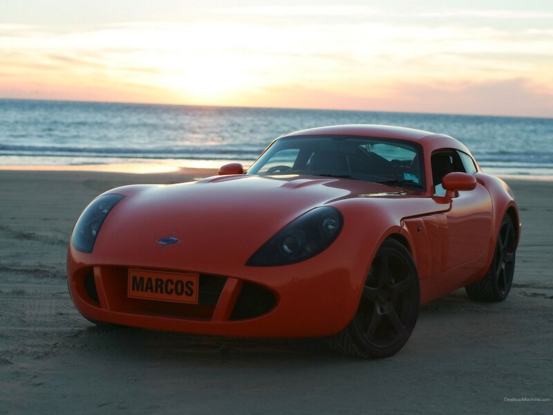 Red sports car on beach at sunset